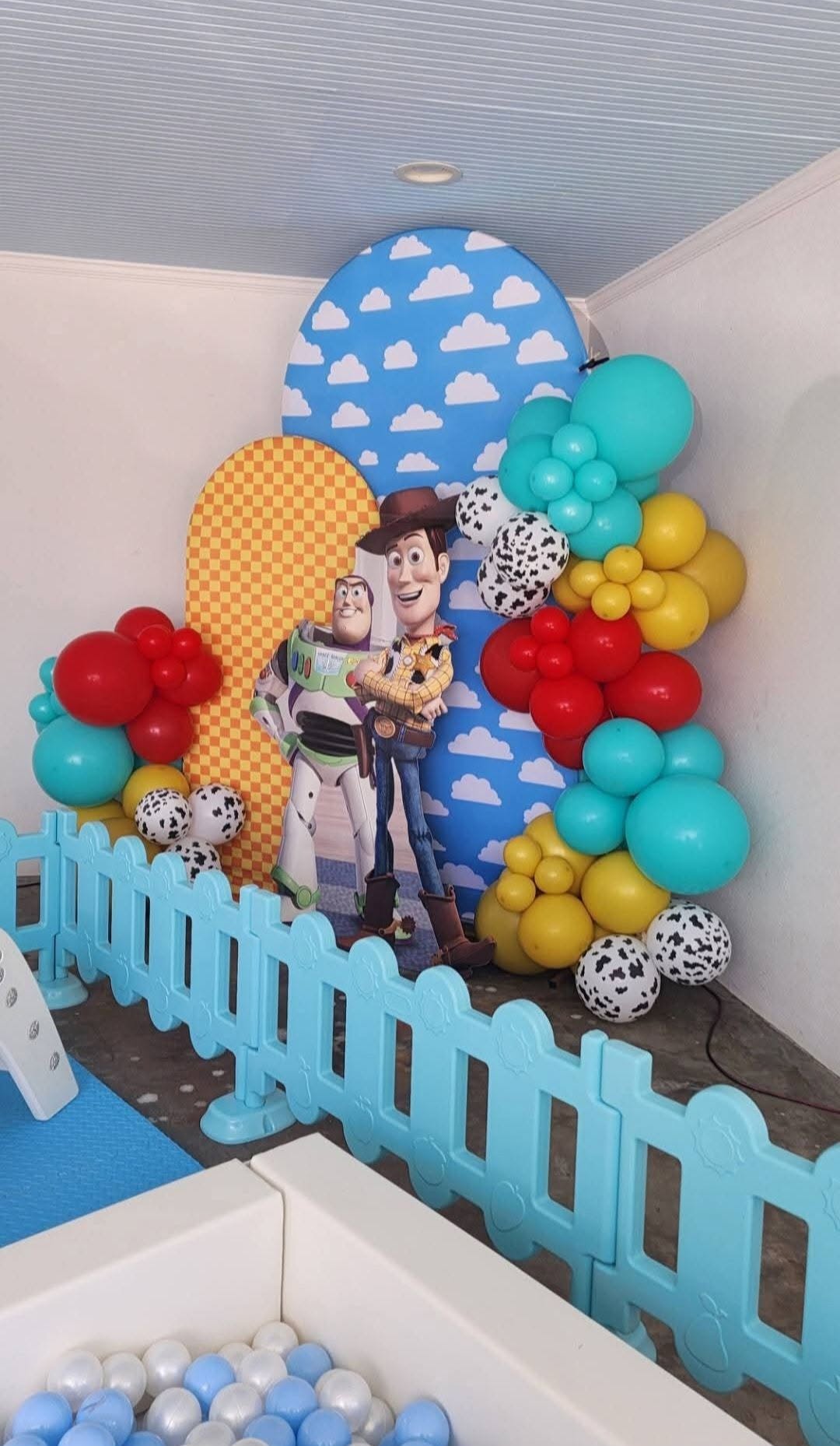 Toy Story themed backdrop with Woody and Buzz, balloon garland and soft play in foreground