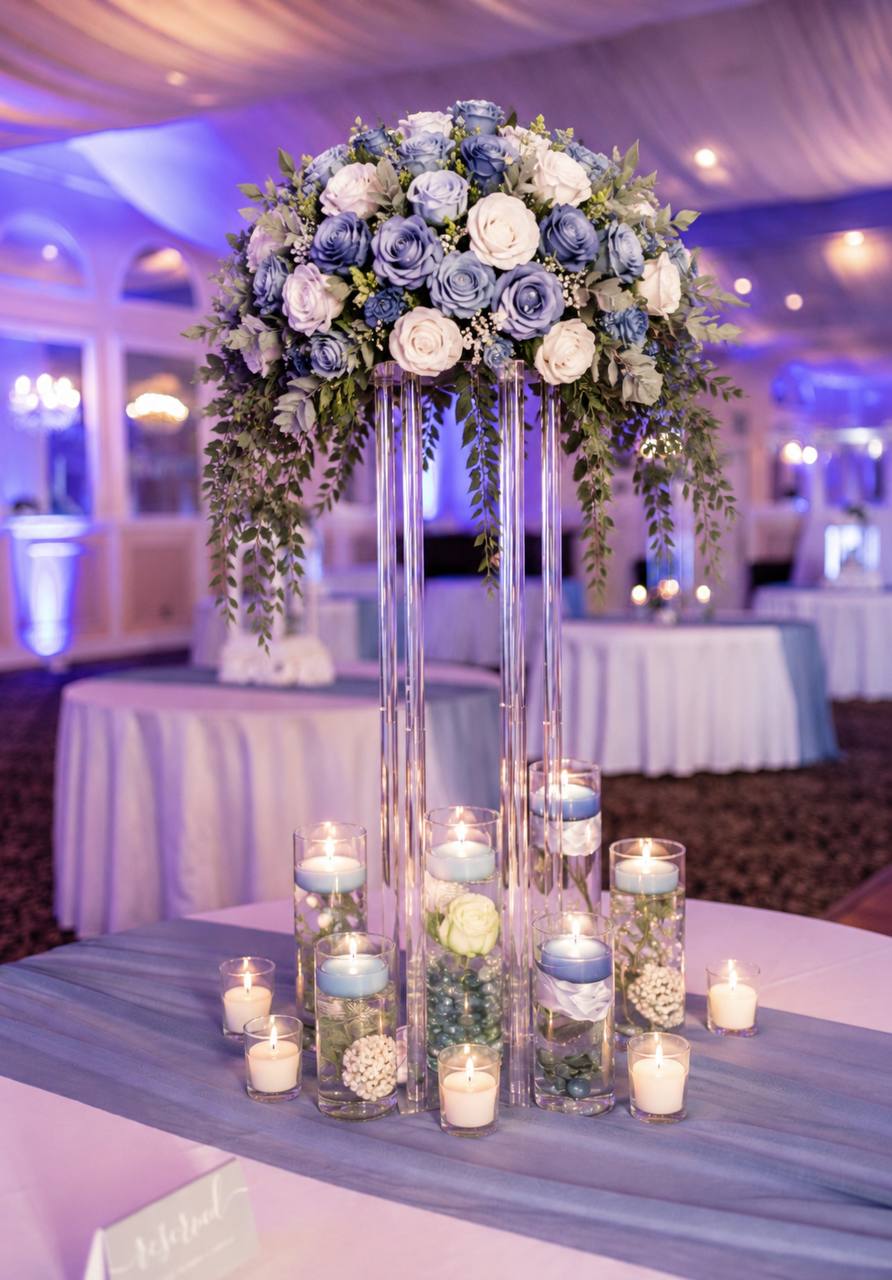 Tall blue-and-ivory rose centerpiece above floating candles at a wedding reception