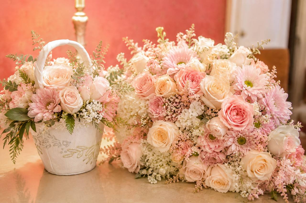 Blush and ivory roses with a lace flower-girl basket on a candlelit table